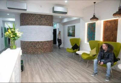 Lounge area with lime green wingback chairs, wood-style flooring, and a curved brick feature wall.