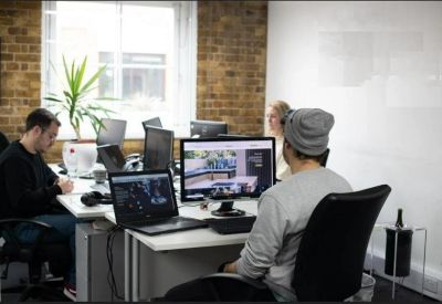 Collaborative workspace with multiple monitors, brick walls, and a large whiteboard.