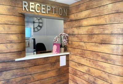 Wooden-paneled reception area with a floral arrangement and a service counter.