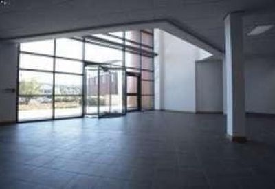 Double-height building entrance lobby with tiled flooring and large glass windows.