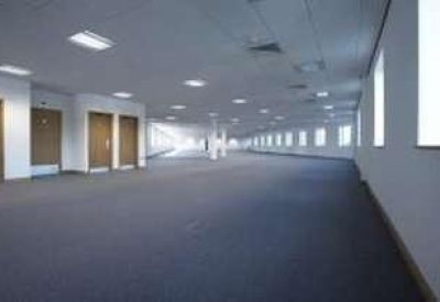 Long, empty office suite with multiple windows, pillars, and several wooden doors.