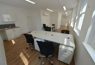 Bright workspace featuring multiple workstations and a compact integrated kitchenette.