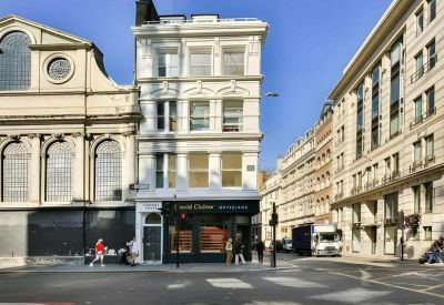 Exterior view of the ornate white facade and ground-floor retail unit.