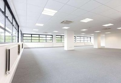 Bright, open-plan office space with white pillars and grid ceiling lighting.