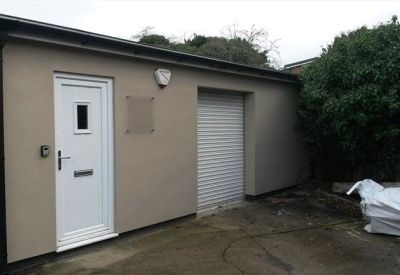 Private entrance with a white door and a security roller shutter.