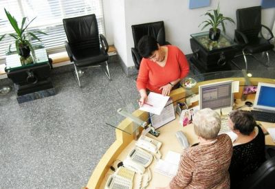 Curved wooden reception desk with staff and modern lounge seating.