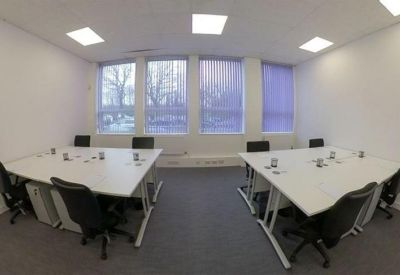 Bright office space with two large white shared workstations and purple window blinds.
