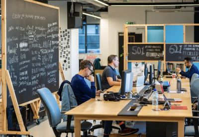 Vibrant coworking area featuring a large chalkboard wall and wooden communal tables.