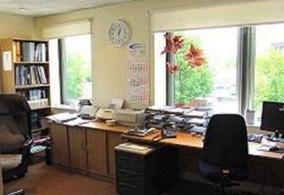 Traditional office space with wooden cabinetry, a large window, and indoor plants.