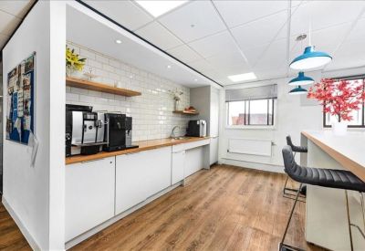 Modern kitchen and breakout area with wood-style flooring and blue pendant lights.