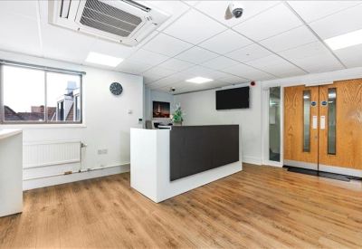 Welcoming reception area with a minimalist white desk and warm wood-effect flooring.