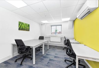 Modern open-plan office with white desks and a bright yellow feature wall.