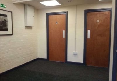 Internal hallway featuring two wooden office doors and a framed picture on the wall.