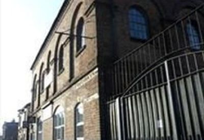 Upward angled view of a historic brick building facade with arched windows and a security gate.