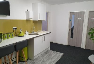 Open-plan communal area with a breakfast bar and green accents.