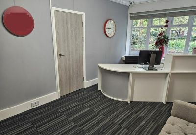 Modern reception area with a curved white desk and red wall accents.