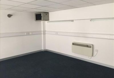 Empty office unit with white walls, blue carpeting, and wall-mounted heating.