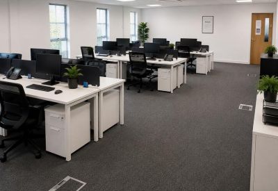 Spacious open-plan workspace with white desks, ergonomic black chairs, and potted plants.