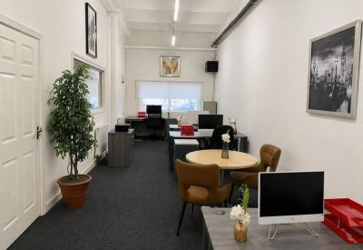 Long open-plan office suite featuring a tall potted plant and a small round meeting table.