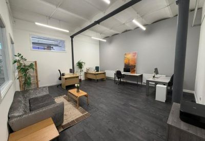 Open office layout featuring a grey sofa lounge area and several workstations.