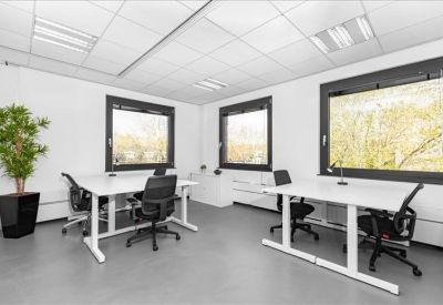 Bright four-person private office with large windows and a potted plant.