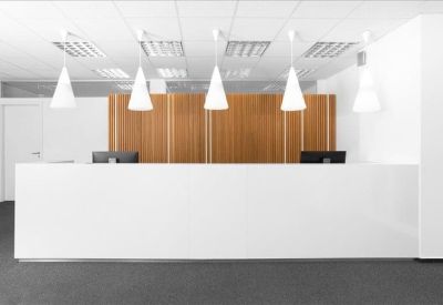 Sleek white reception desk backed by a warm wood-paneled feature wall.
