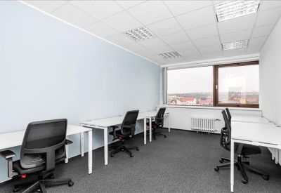Bright office room with white desks, black chairs, and a large window.