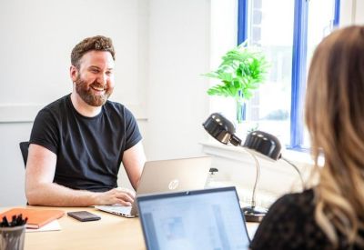 Close-up of professionals collaborating at a desk with laptops and natural light.