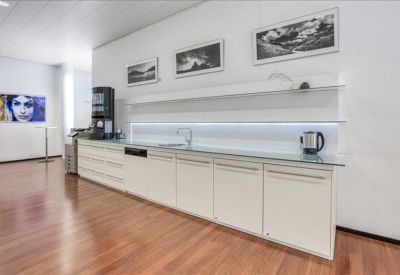 Modern communal kitchen area with wood flooring and white cabinetry.