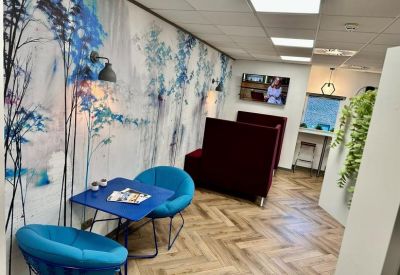 Modern lounge area with blue chairs, a chevron floor, and a nature-inspired feature wall.