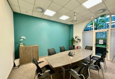 Meeting room with a teal feature wall, large window, and oval wooden table.
