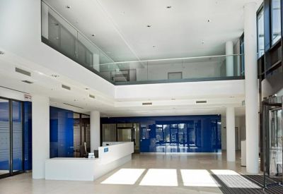 Spacious double-height reception lobby with a white front desk and blue glass partitions.