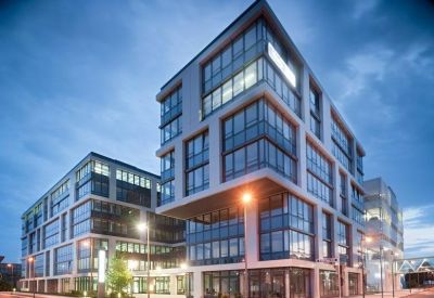 Exterior view of the multi-story glass office complex with illuminated windows.