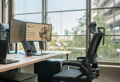 Private workstation with ergonomic chair and dual monitors next to a large window.