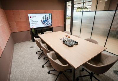 Contemporary meeting room with a wall-mounted screen and terracotta-toned acoustic panels.