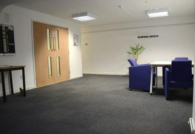 Bright reception waiting area with blue armchairs and large double doors.