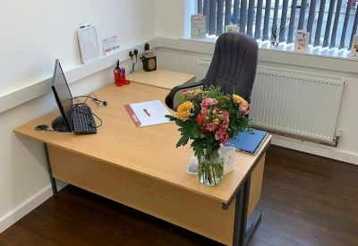 Private office suite with a wood-finish desk, ergonomic chair, and a fresh bouquet of flowers.