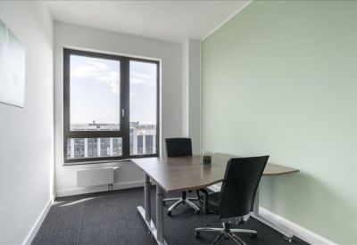 Bright private office featuring a wooden desk and a light green accent wall.