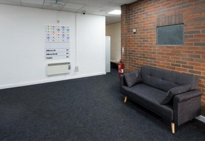 Lounge area with a dark sofa against a red brick feature wall.