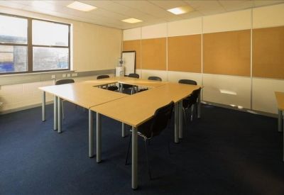 Professional meeting room with a large square conference table and blue carpeting.