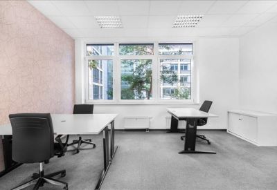 Modern three-person office suite with pink feature wall and large window.