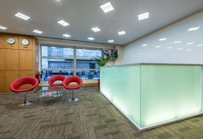 Reception area with red chairs and a modern desk.