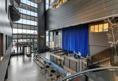 Spacious communal atrium with a blue stage backdrop and modern seating arrangements.