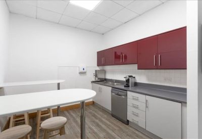 Modern kitchen and break area with red cabinetry and a breakfast bar with stools.
