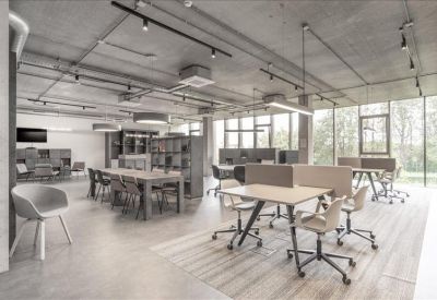 Spacious communal coworking area with industrial ceilings and various seating arrangements.