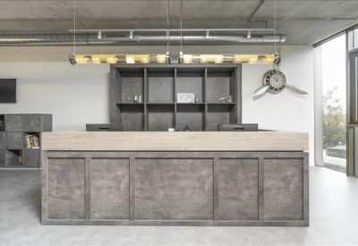 Minimalist reception desk with a large textured grey front and industrial pendant lighting.