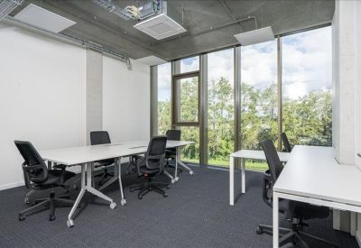 Modern private office with a white desk, ergonomic chairs, and large windows.