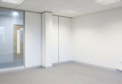 Bright empty office room with white walls and a wood-veneer door.