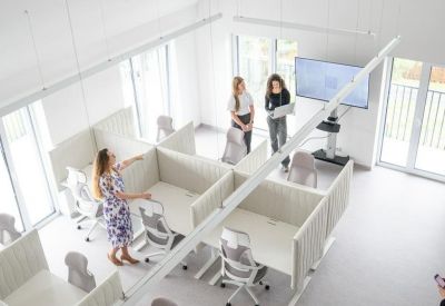 Spacious, high-ceiling coworking area at Dykova 1090/19 with modern cubicles and a wall-mounted presentation screen.