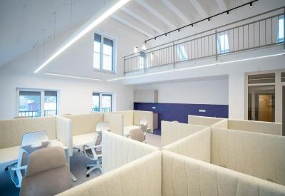 Open-plan office with individual workstations, a mezzanine level, and a deep blue feature wall.